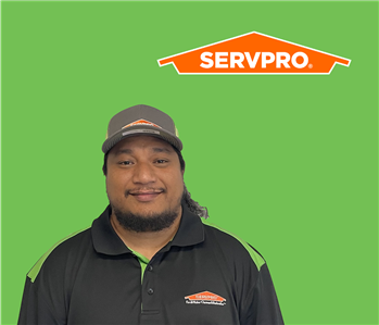 SERVPRO employee with a hat wearing a black shirt in front of a green background