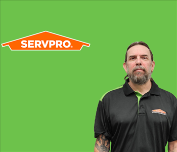 SERVPRO employee with dark hair wearing a black shirt in front of a green background